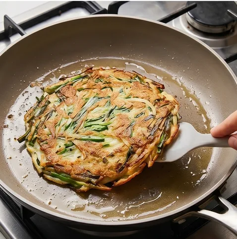 초간단 부추전 | 부추를 맛있게 많이 먹게되는 바삭한 부추전 레시피 조리 단계 5 이미지 - 가장자리가 노릇해지면 뒤집고, 팬을 살짝 흔들어가며 1~2분 더 구워 마