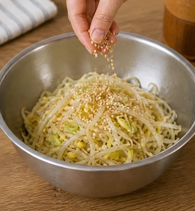 콩나물무침 레시피 | 아삭한 식감 살리는 데친 콩나물 조리 단계 7 이미지 - 무친 콩나물 위에 통깨 1작은술을 골고루 뿌려 마무리해줍니다.